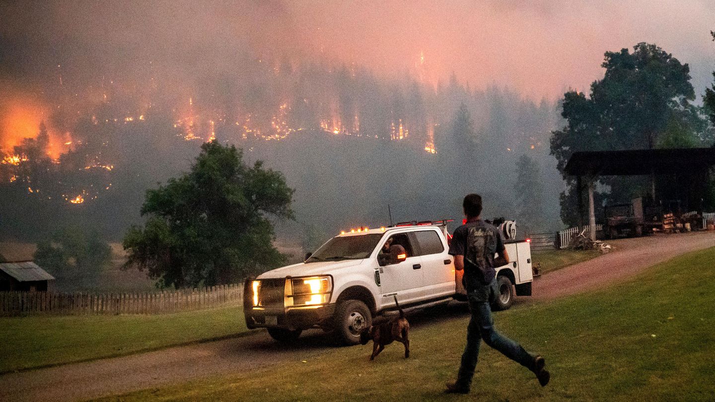 Ein Mann läuft zu einem Auto, während in Hintergrund das McKinney-Feuer im Klamath National Forest in Kalifornien wütet.