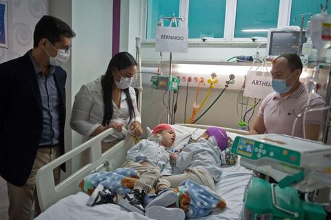Nach der OP stehen die Eltern der Zwillinge am Krankenbett ihrer Kinder
