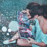 Eine Frau liest ein Buch und pustet Konfetti weg.