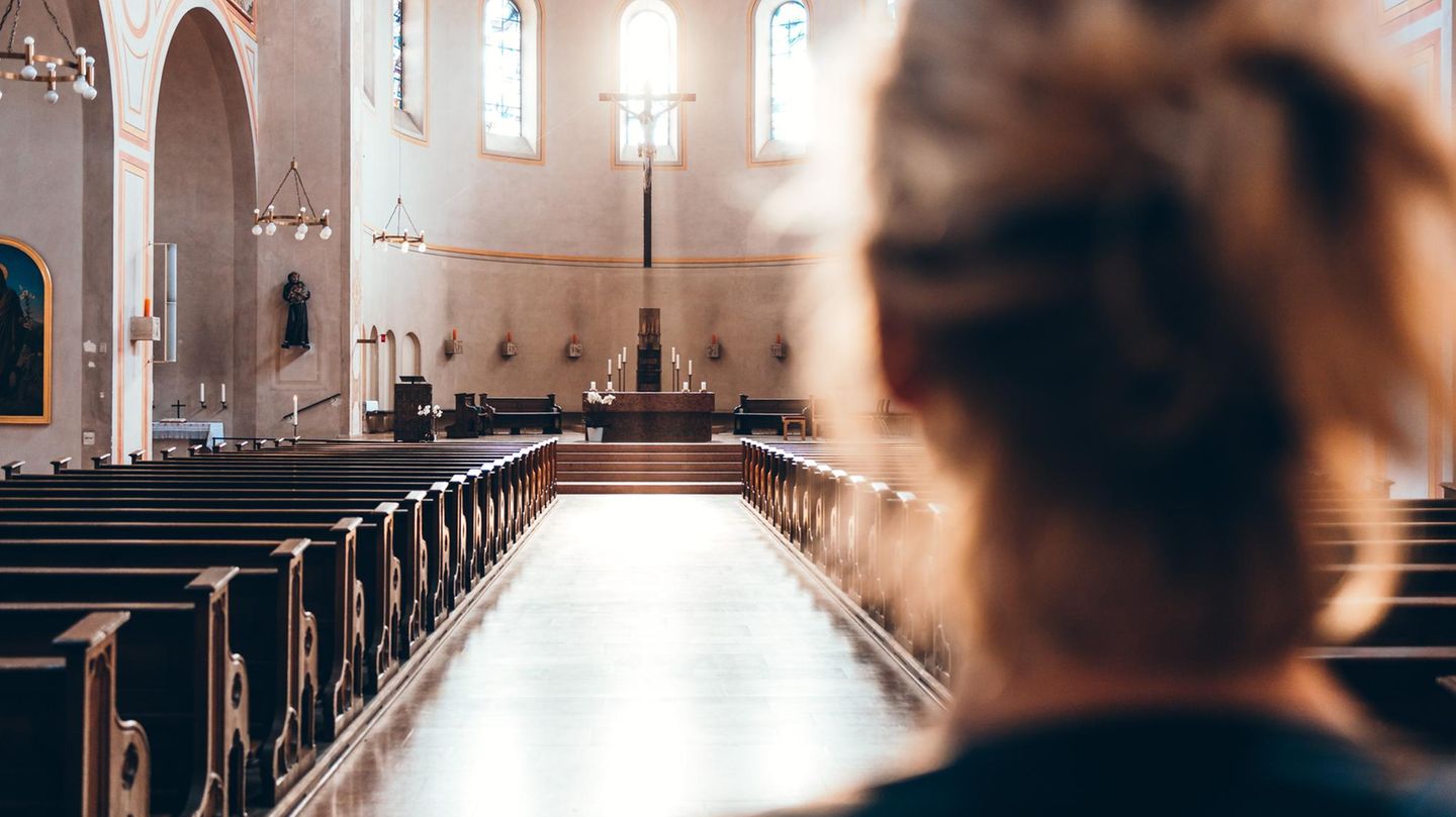 Eine Frau steht in der Kirche mit Blick auf den Altar.