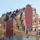 Männer im Blaumann bauen ein neues Holzhaus.
