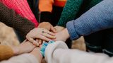 Viele Menschen legen ihre Hände aufeinander.