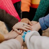 Viele Menschen legen ihre Hände aufeinander.