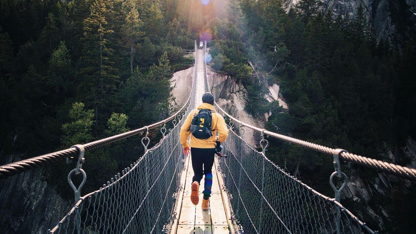 Ein Mann rennt eine Hängebrücke entlang.