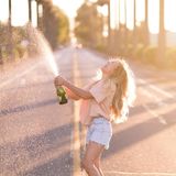 Eine Frau öffnet lachend eine Sektflasche.