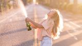 Eine Frau öffnet lachend eine Sektflasche.