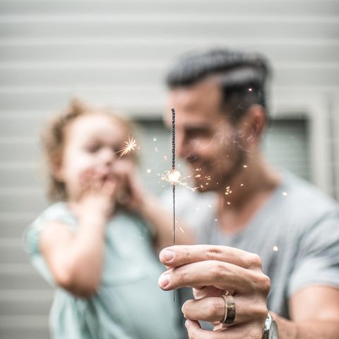 Eine Mann hält mit seiner Tochter eine Wunderkerze in der Hand.