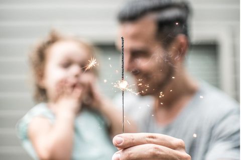 Eine Mann hält mit seiner Tochter eine Wunderkerze in der Hand.