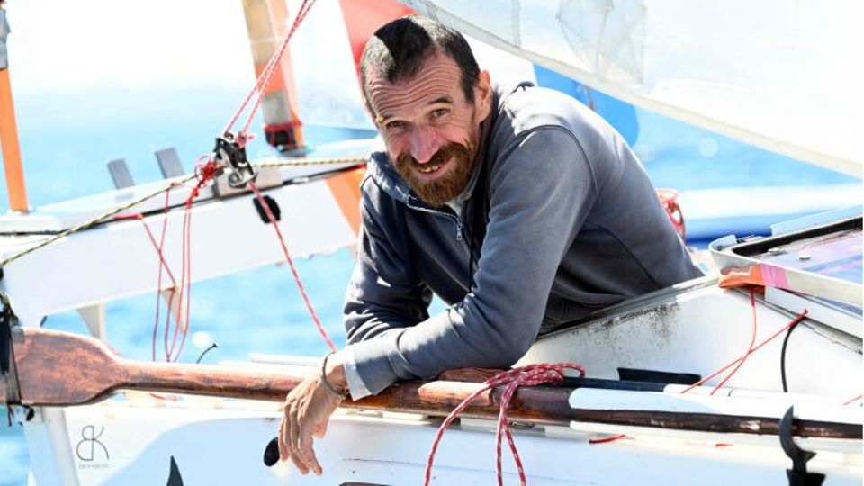 Yann Quénet lächelt an Bord seiner "Baluchon" in die Kamera