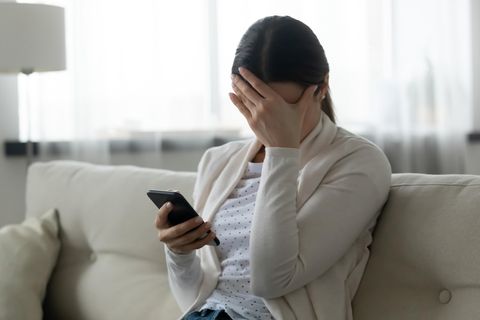 Eine junge Frau hält sich die Hand vor die Stirn