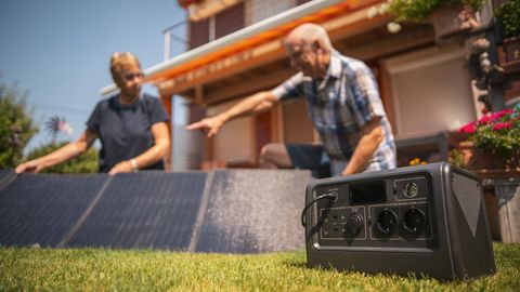 Zwei Personen bauen Solarpenals für einen Solargenerator auf.