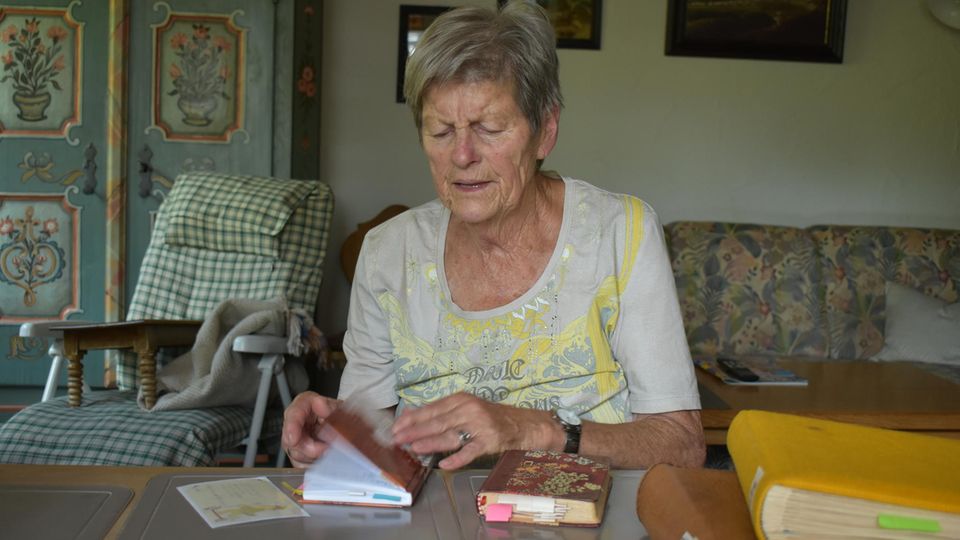 Seniorin sitzt am Tisch mit Reisetagebüchern