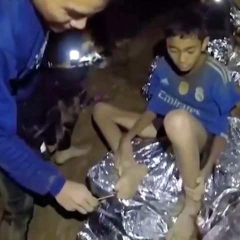 Thailand, 3. Juli 2018: Ein Jugendlicher der Fußballmannschaft, die in einer Höhle in Thailand eingeschlossen ist, wird von einem Navy Seal versorgt