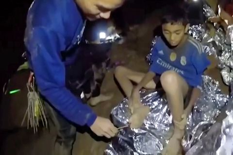 Thailand, 3. Juli 2018: Ein Jugendlicher der Fußballmannschaft, die in einer Höhle in Thailand eingeschlossen ist, wird von einem Navy Seal versorgt