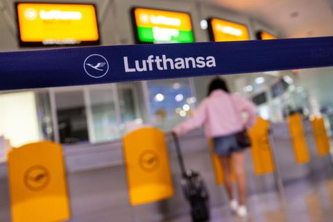 Eine Passagierin wartet an einem Lufthansa Service-Schalter am Flughafen München vorbei