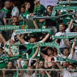 Fans von Werder Bremen stehen mit ihren Schals auf der Tribüne