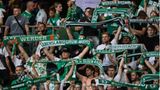 Fans von Werder Bremen stehen mit ihren Schals auf der Tribüne