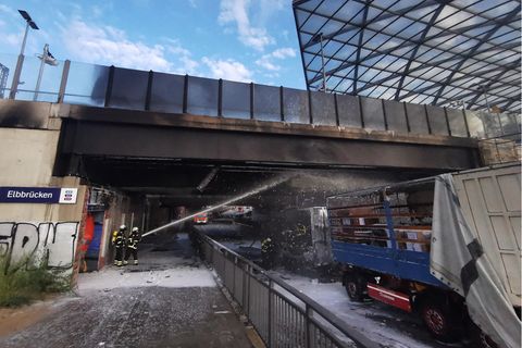 Hamburg: Zwei Feuerwehrleute löschen einen brennenden LKW, der unter einer Brücke steht