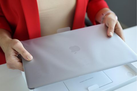 Apple MacBook Air M1 vs. M2: Eine Frau hält ein neues Apple MacBook M1 in der Hand.