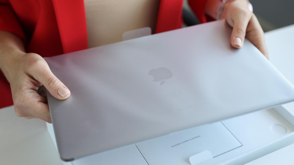 Apple MacBook Air M1 vs. M2: Eine Frau hält ein neues Apple MacBook M1 in der Hand.