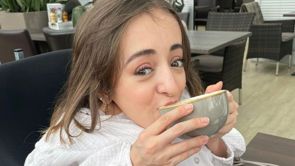 Frau im Rollstuhl trinkt einen Kaffee