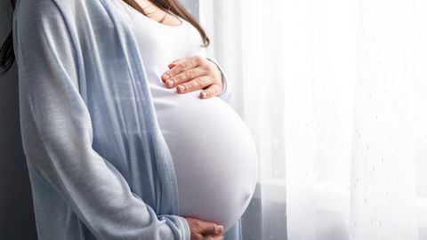 Eine schwangere Frau am Fenster – wann eine Corona-Infektion gefährlich ist