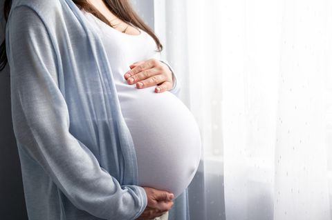 Eine schwangere Frau am Fenster – wann eine Corona-Infektion gefährlich ist
