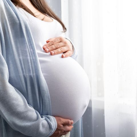 Eine schwangere Frau am Fenster – wann eine Corona-Infektion gefährlich ist