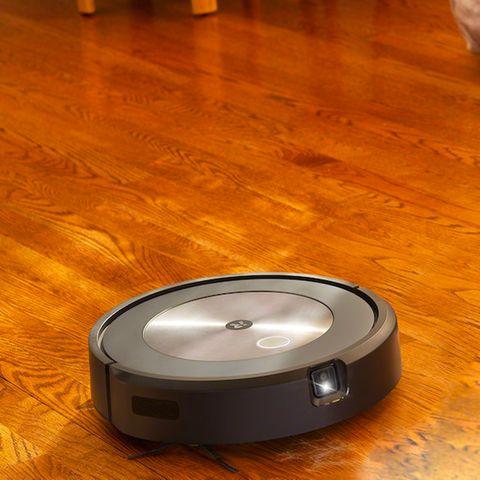 Ein Roomba-Roboter fährt durch ein Zimmer, im Hintergrund ein Hund