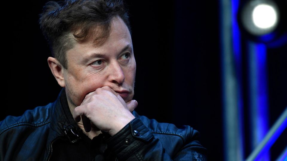 Elon Musk hält seine linke Hand vor den Mund