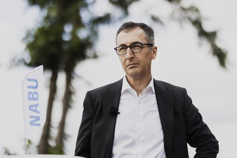 Cem Özdemir mit NABU-Flagge im Hintergrund