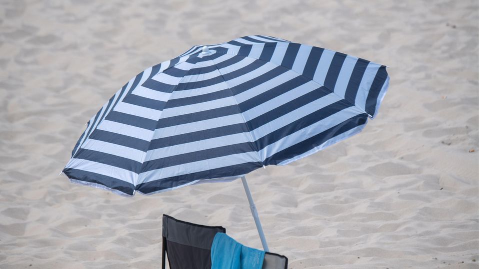 Ein Sonnenschirm steht bei sonnigem Wetter am Strand