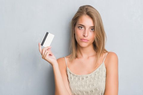 Eine vorwurfsvoll dreinblickende Frau mit einer Kreditkarte in der Hand