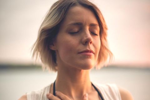 Eine Frau hält sich mit geschlossenen Augen die Hand aufs Herz.