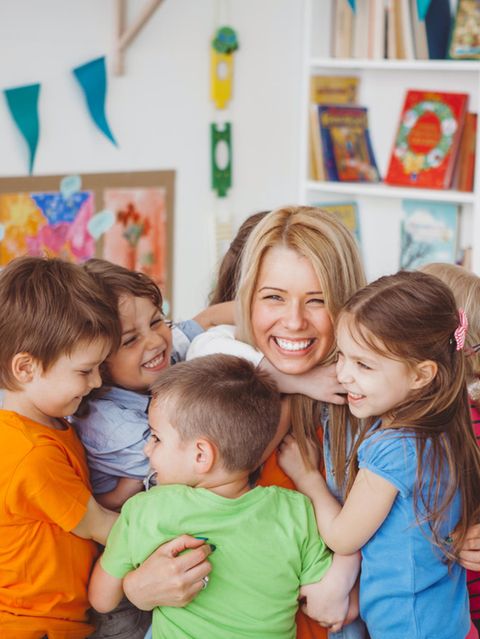 Kinder umarmen Erzieherin im Kindergarten