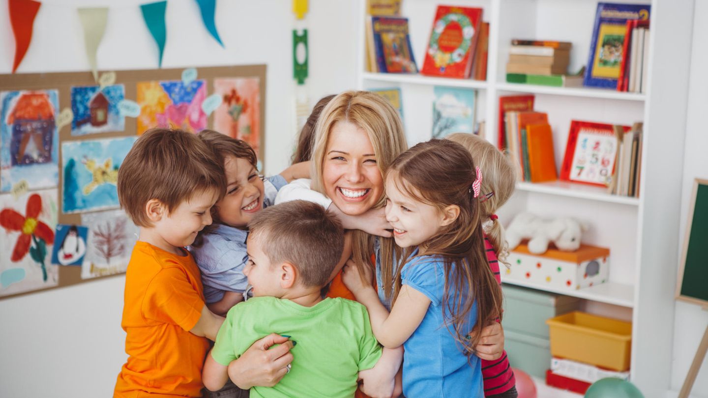 Kinder umarmen Erzieherin im Kindergarten