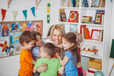 Kinder umarmen Erzieherin im Kindergarten