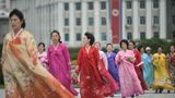 Frauen gehen in der Nähe des Triumphbogens der Hauptstadt in traditionellen koreanischen Hanbok-Kleidern spazieren