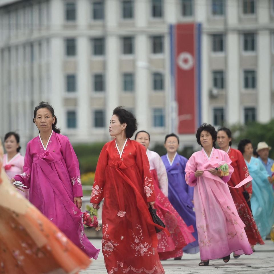 Frauen gehen in der Nähe des Triumphbogens der Hauptstadt in traditionellen koreanischen Hanbok-Kleidern spazieren