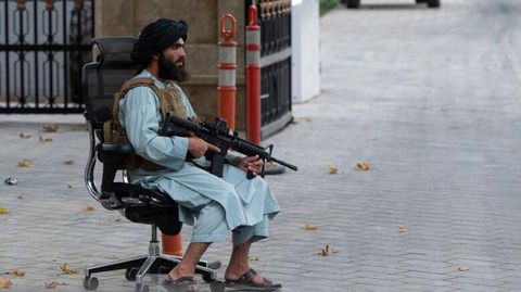 Taliban sitzt mit Maschinengewehr auf Bürostuhl