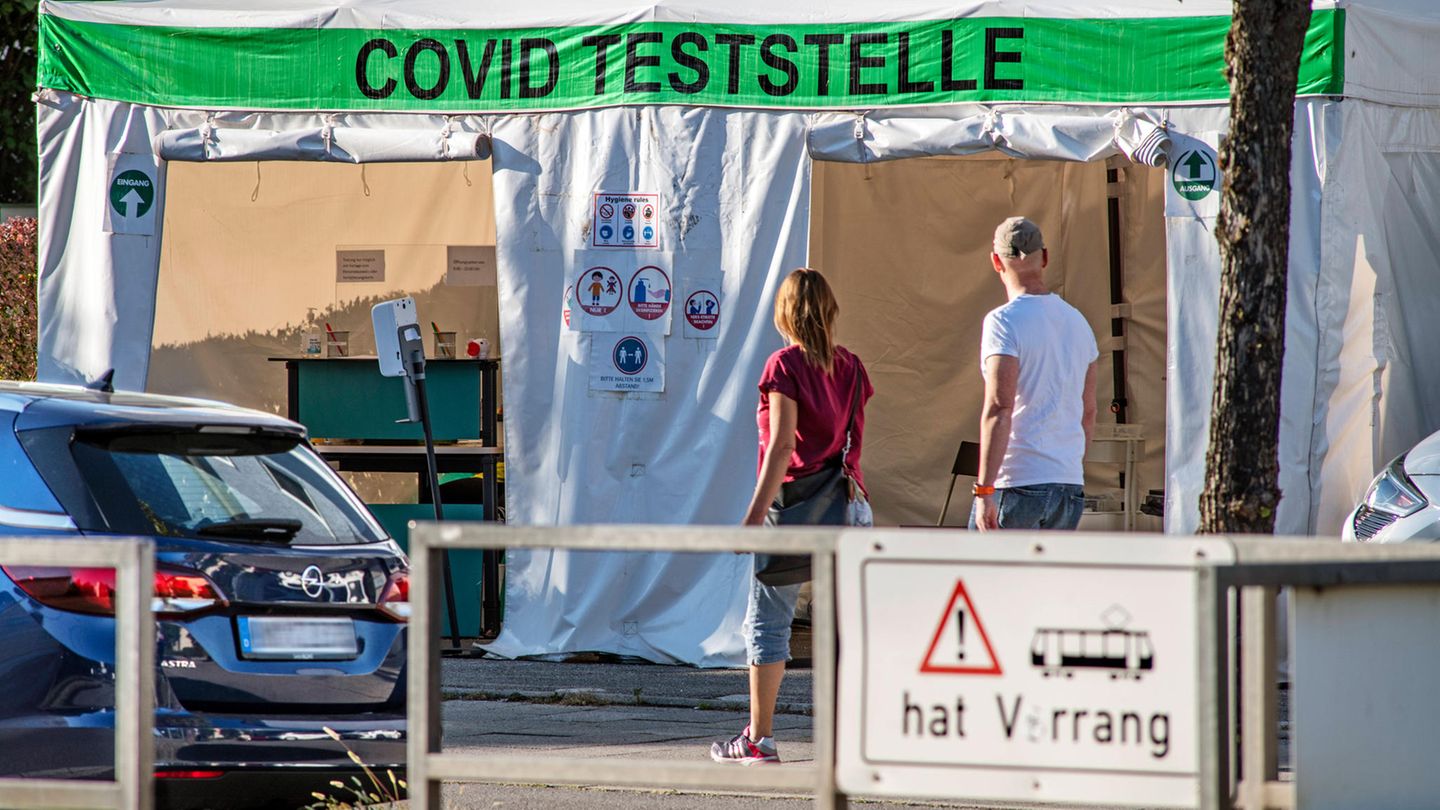 Passanten gehen vor einer Corona-Teststelle vorbei