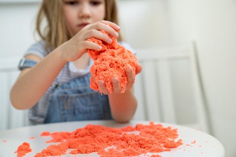 Kleines Mädchen, das mit kinetischem Sand spielt