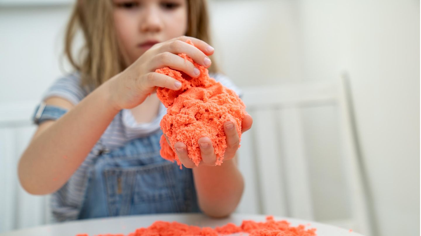 Kleines Mädchen, das mit kinetischem Sand spielt