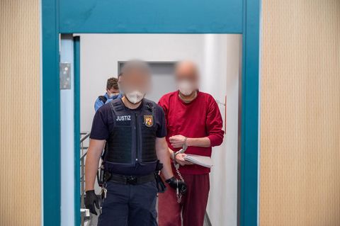 Ein Justizbediensteter begleitet den 52-jährigen Angeklagten (r) zum Prozess