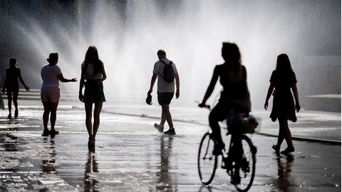 In Wien erfrischen sich Menschen auf dem Karlsplatz