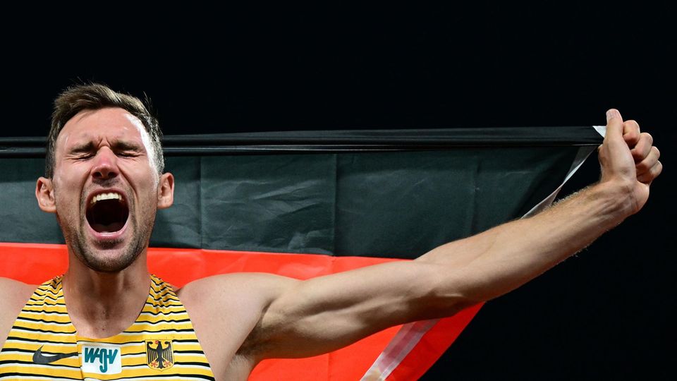 Ein junger weißer Mann jubelt mit offenem Mund und geschlossenen Augen. Er trägt ein gelb-schwarzes Trikot mit Bundesadler