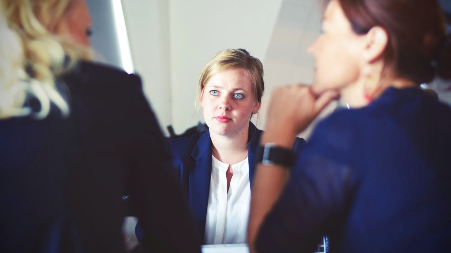Eine Frau sitzt zwei anderen Frauen im Büro gegenüber.