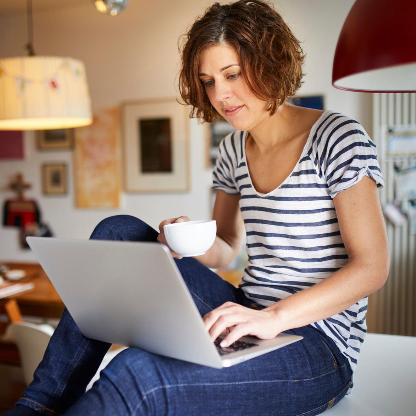 Portrait of mature woman sitting on kitchen table using laptop