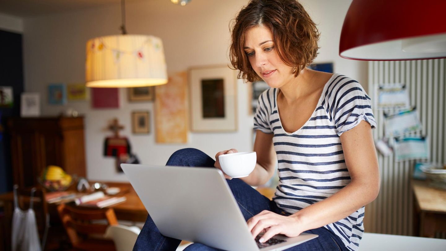 Portrait of mature woman sitting on kitchen table using laptop