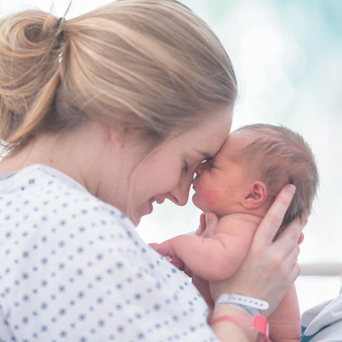 Eine Mutter hält glücklich ihr Neugeborenes im Arm  Eine Mutter hält glücklich ihr Neugeborenes im Arm